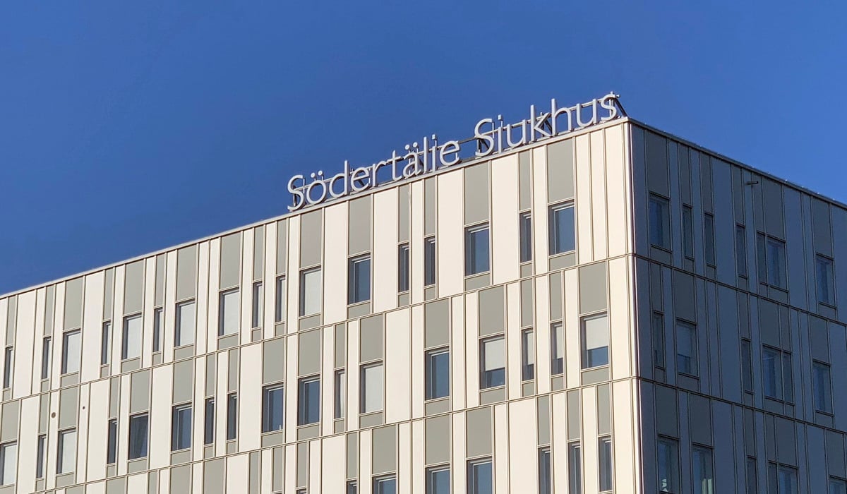Södertälje sjukhus exteriör med loggan mot en blå himmel
